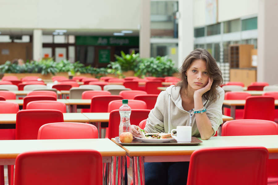 Portrait of a alone and sad female student sitting in the cafete